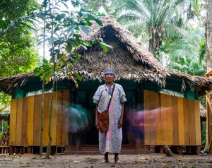 Manuel standing in front of a hut.