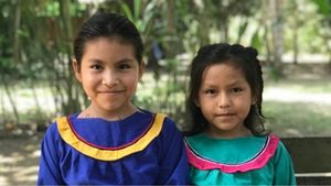 Profiles of two Shipibo children smiling at camera.